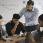 Team members in a workplace showing signs of stress while a manager offers support, representing organizational trauma and recovery at work.