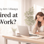 Tired businesswoman sitting at desk with laptop and coffee looking exhausted at work in a bright modern office